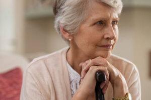 An older woman with her hands on a cane wonders if owning a home can affect their Medicaid eligibility.