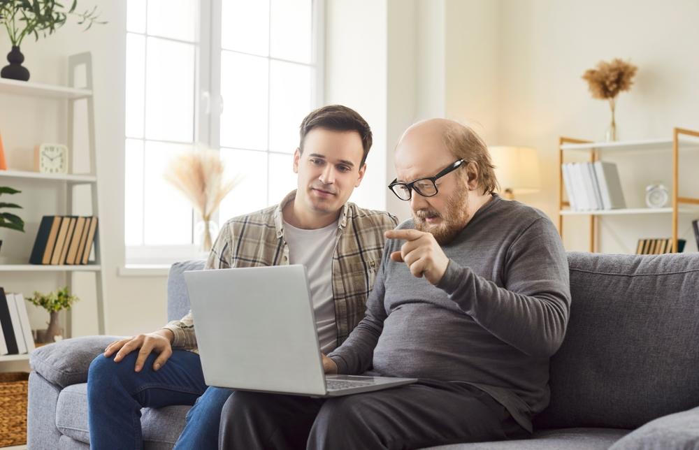 A man helps his older father use a computer to research what a revocable trust is.